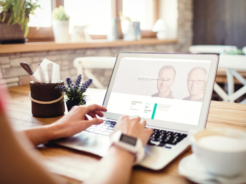 Frau mit Laptop betrachtet die Website der HNO Praxis im DEZ